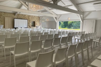 Salle de réception décorée avec des guirlandes lumineuses, des lampions suspendus et des tables dressées pour un événement.