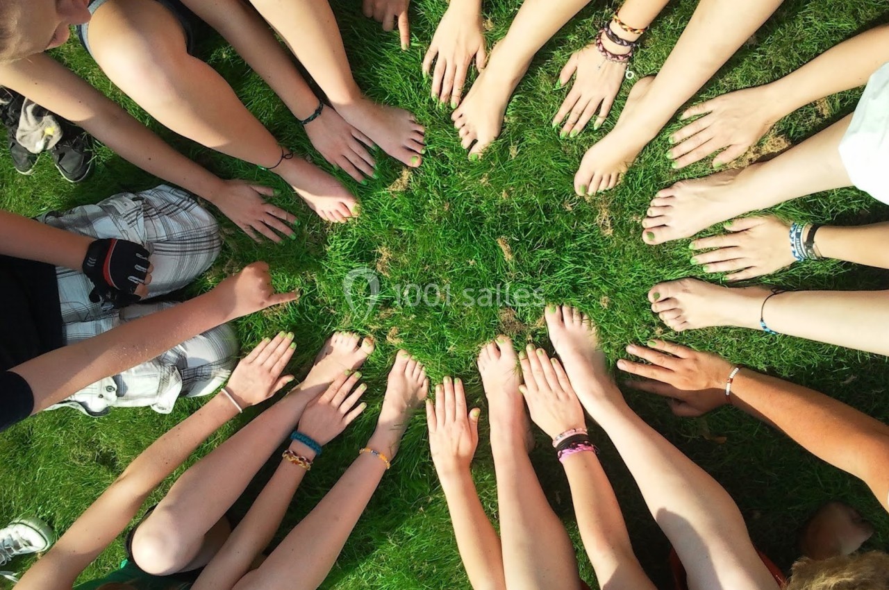 Des mains et pieds nus disposés en cercle sur de l'herbe verte.