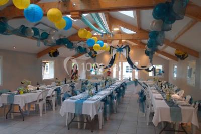 Chalet en bois entouré de végétation, avec terrasse équipée de mobilier de jardin sous un arbre.