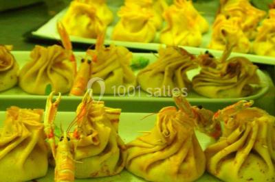 Chalet en bois entouré de végétation, avec terrasse équipée de mobilier de jardin sous un arbre.