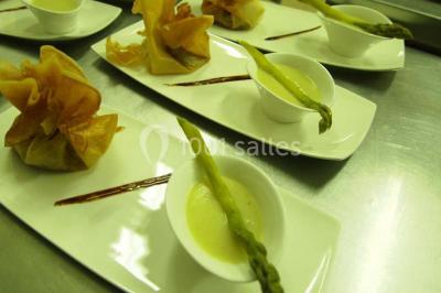 Chalet en bois entouré de végétation, avec terrasse équipée de mobilier de jardin sous un arbre.
