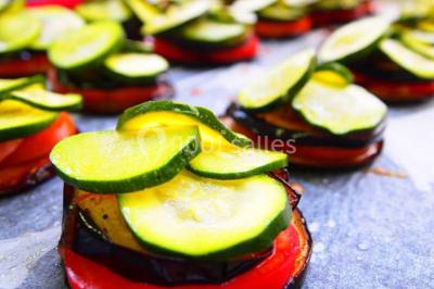 Chalet en bois entouré de végétation, avec terrasse équipée de mobilier de jardin sous un arbre.