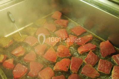 Chalet en bois entouré de végétation, avec terrasse équipée de mobilier de jardin sous un arbre.