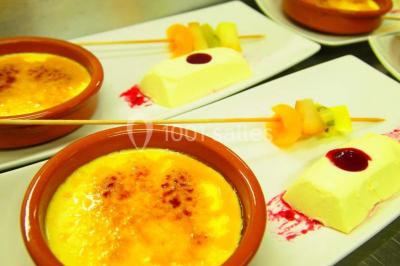 Chalet en bois entouré de végétation, avec terrasse équipée de mobilier de jardin sous un arbre.