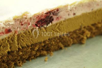 Chalet en bois entouré de végétation, avec terrasse équipée de mobilier de jardin sous un arbre.
