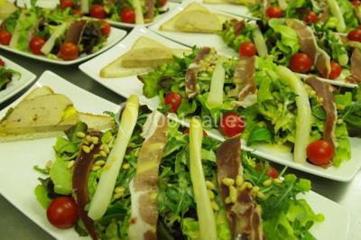 Chalet en bois entouré de végétation, avec terrasse équipée de mobilier de jardin sous un arbre.