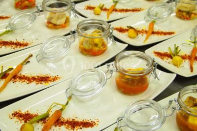 Chalet en bois entouré de végétation, avec terrasse équipée de mobilier de jardin sous un arbre.
