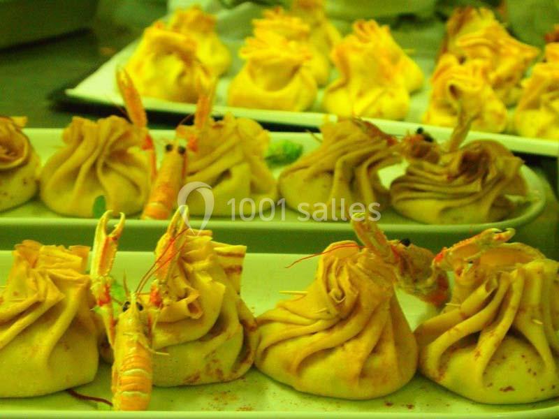 Assiettes de ravioles dorées garnies de crevettes, disposées sur un plan de travail en cuisine.