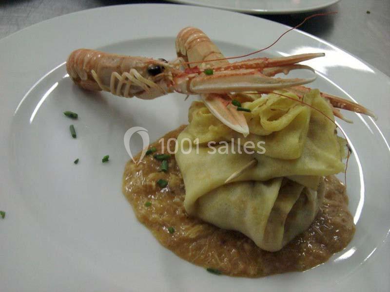 Crêpe garnie sur sauce crémeuse, décorée d'une langoustine entière et de ciboulette hachée.