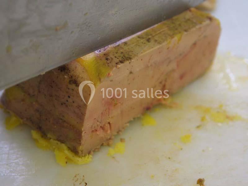 Bloc de foie gras tranché sur une planche, avec une couche de graisse jaune visible.