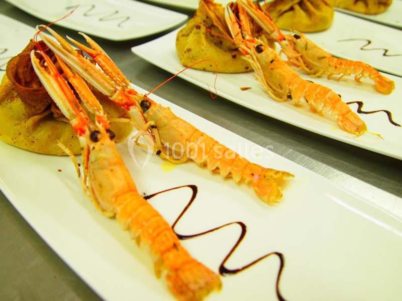 Assiettes garnies de langoustines dressées sur des crêpes avec un filet de sauce décorative.