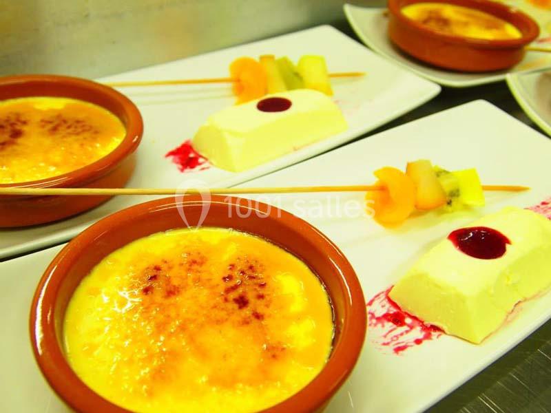 Desserts présentés sur des assiettes : crèmes brûlées, brochettes de fruits et entremets avec coulis rouge.