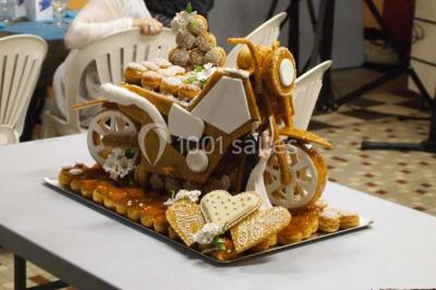 Pièce montée en forme de moto, composée de choux et nougatine, présentée sur une table dans une salle.