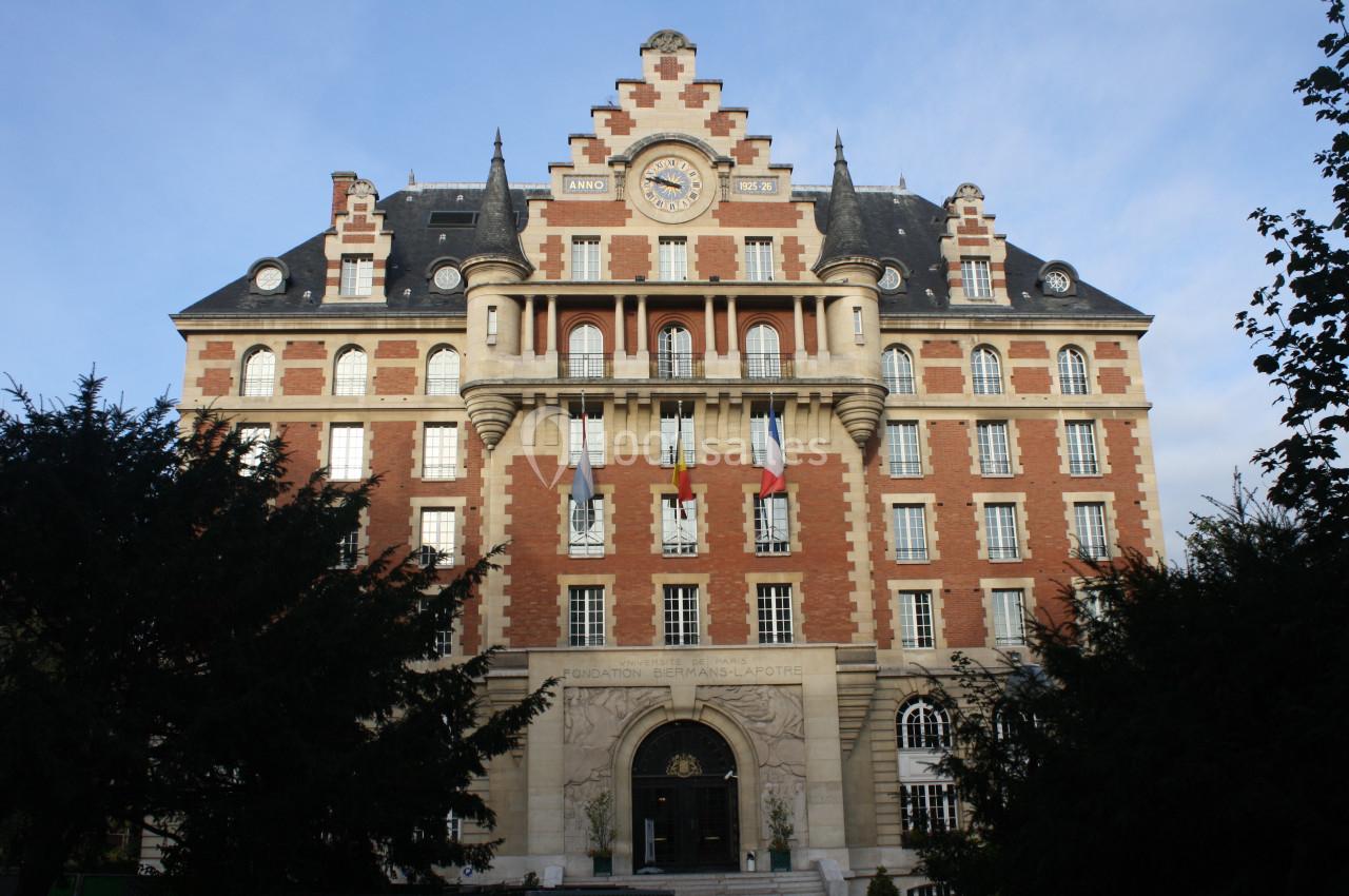 Façade d'un bâtiment en briques rouges et pierre avec une horloge centrale et des détails architecturaux ornés.