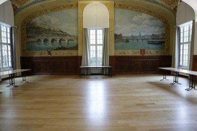 Écran de projection blanc dans une petite salle équipée de fauteuils marron et de haut-parleurs muraux.
