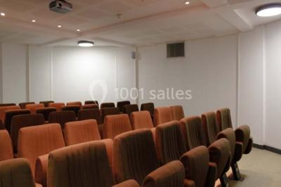 Banc en pierre au premier plan dans une allée bordée d'arbres, avec des promeneurs visibles au loin.