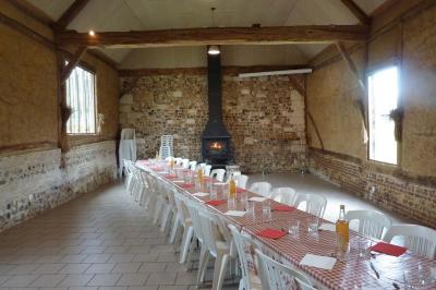 Miniature Location salle Montivilliers (Seine-Maritime) - Ferme d'Epaville #19 Salle rustique avec murs en pierre et poutres apparentes, aménagée avec tables hautes, canapés et décorations simples.