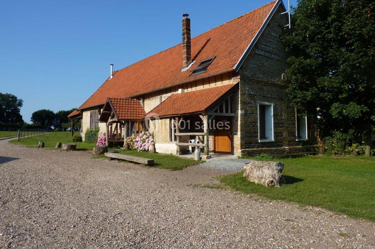 Location salle Montivilliers (Seine-Maritime) - Ferme d'Epaville #27 Maison en pierre avec toit en tuiles rouges, entourée de verdure et d'un chemin de gravier sous un ciel dégagé.