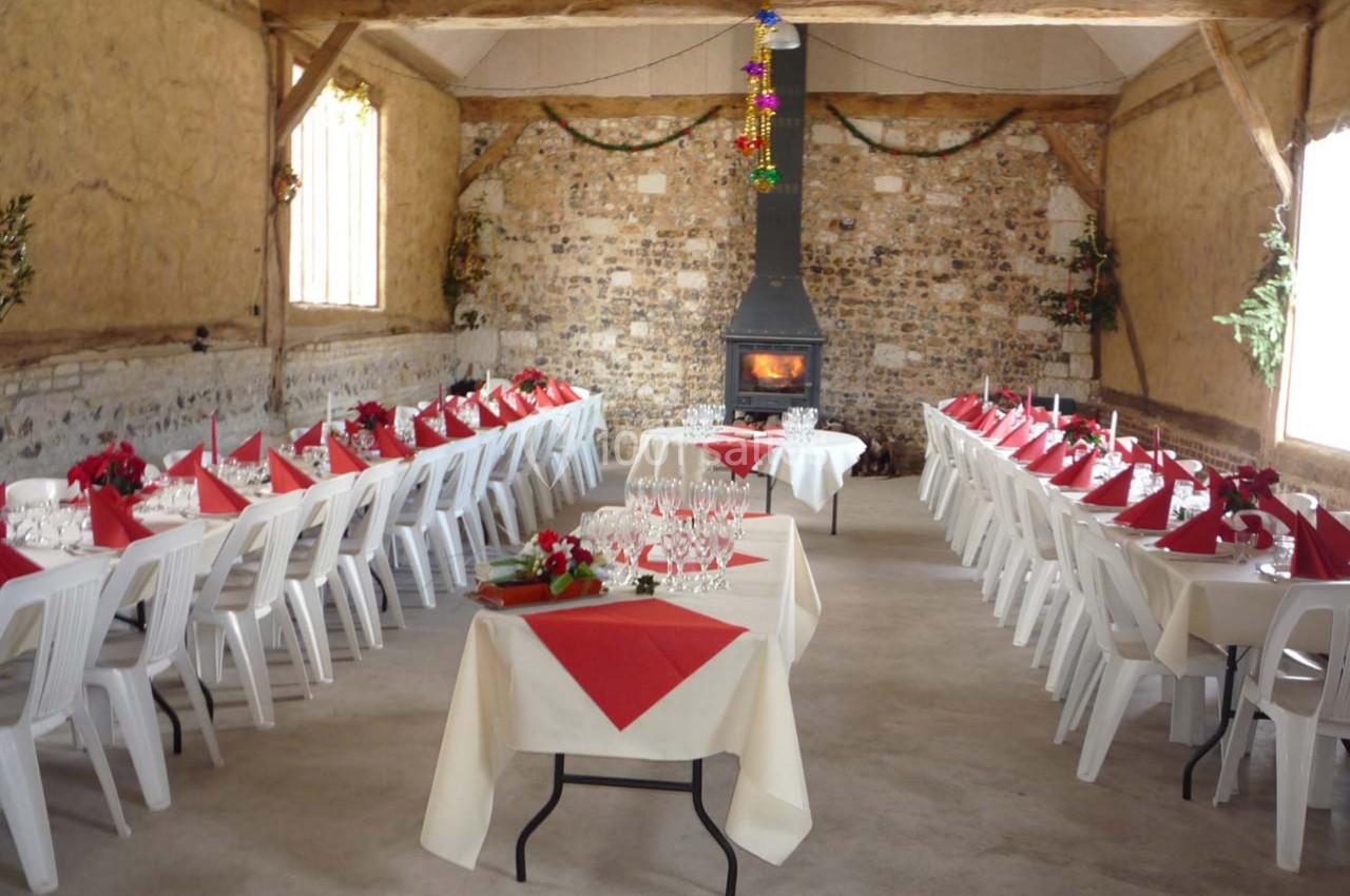 Location salle Montivilliers (Seine-Maritime) - Ferme d'Epaville #39 Salle rustique décorée pour un repas festif, avec longues tables dressées, nappes blanches et cheminée allumée.