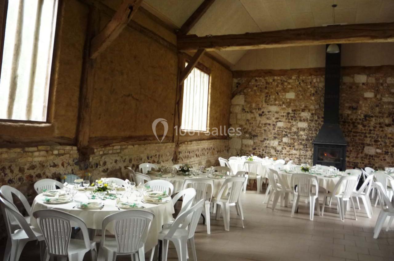 Location salle Montivilliers (Seine-Maritime) - Ferme d'Epaville #15 Salle rustique avec murs en pierre et poutres apparentes, tables rondes dressées avec nappes blanches et chaises en…