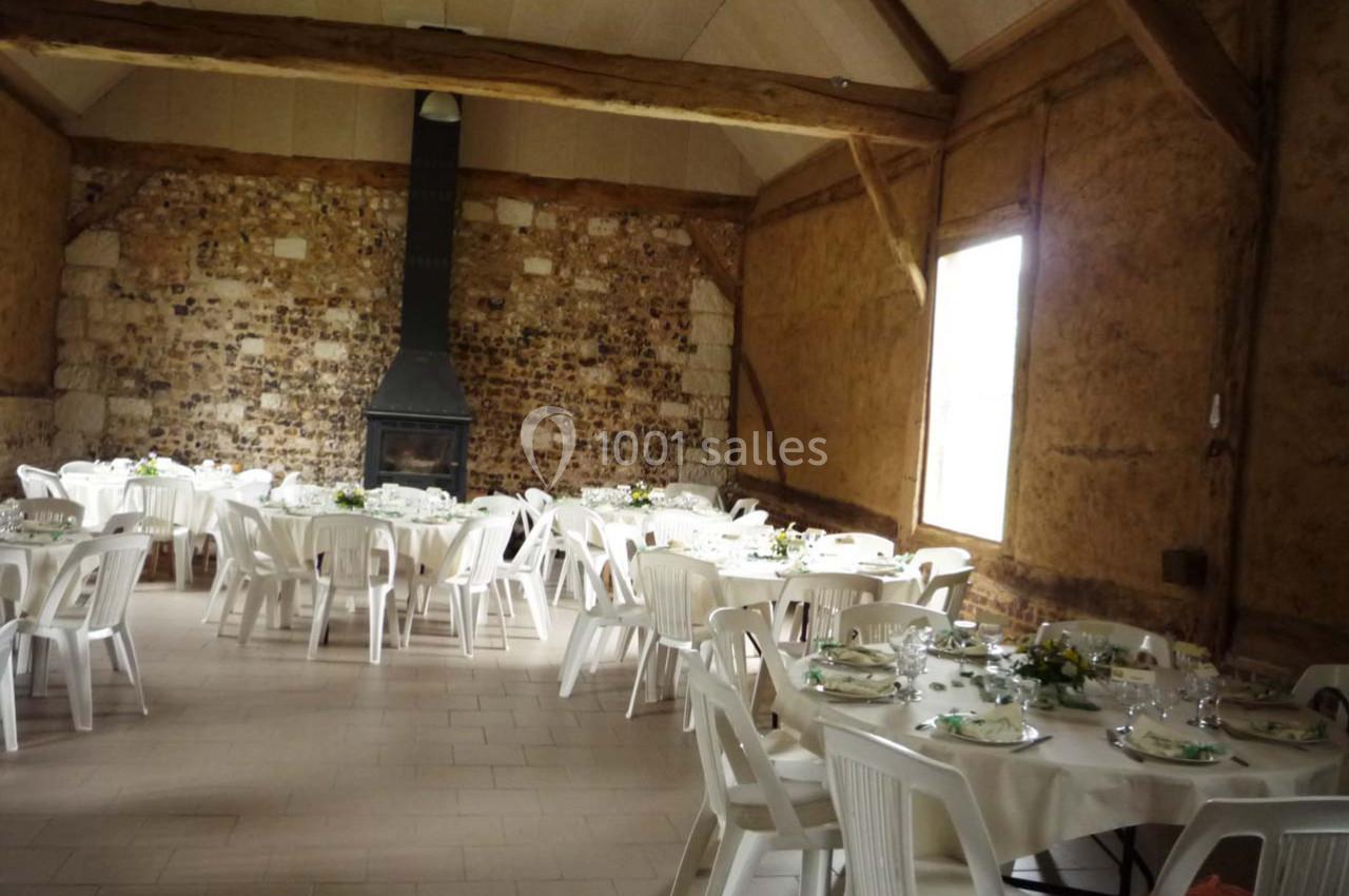 Location salle Montivilliers (Seine-Maritime) - Ferme d'Epaville #17 Salle rustique avec murs en pierre et poutres apparentes, tables rondes dressées avec nappes blanches et chaises en…