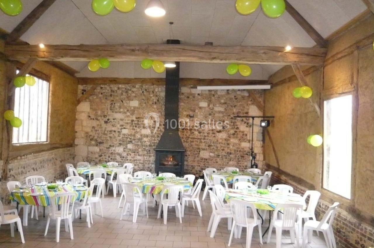 Location salle Montivilliers (Seine-Maritime) - Ferme d'Epaville #21 Salle rustique décorée de ballons verts et jaunes, tables rondes dressées avec nappes colorées et chaises blanches.