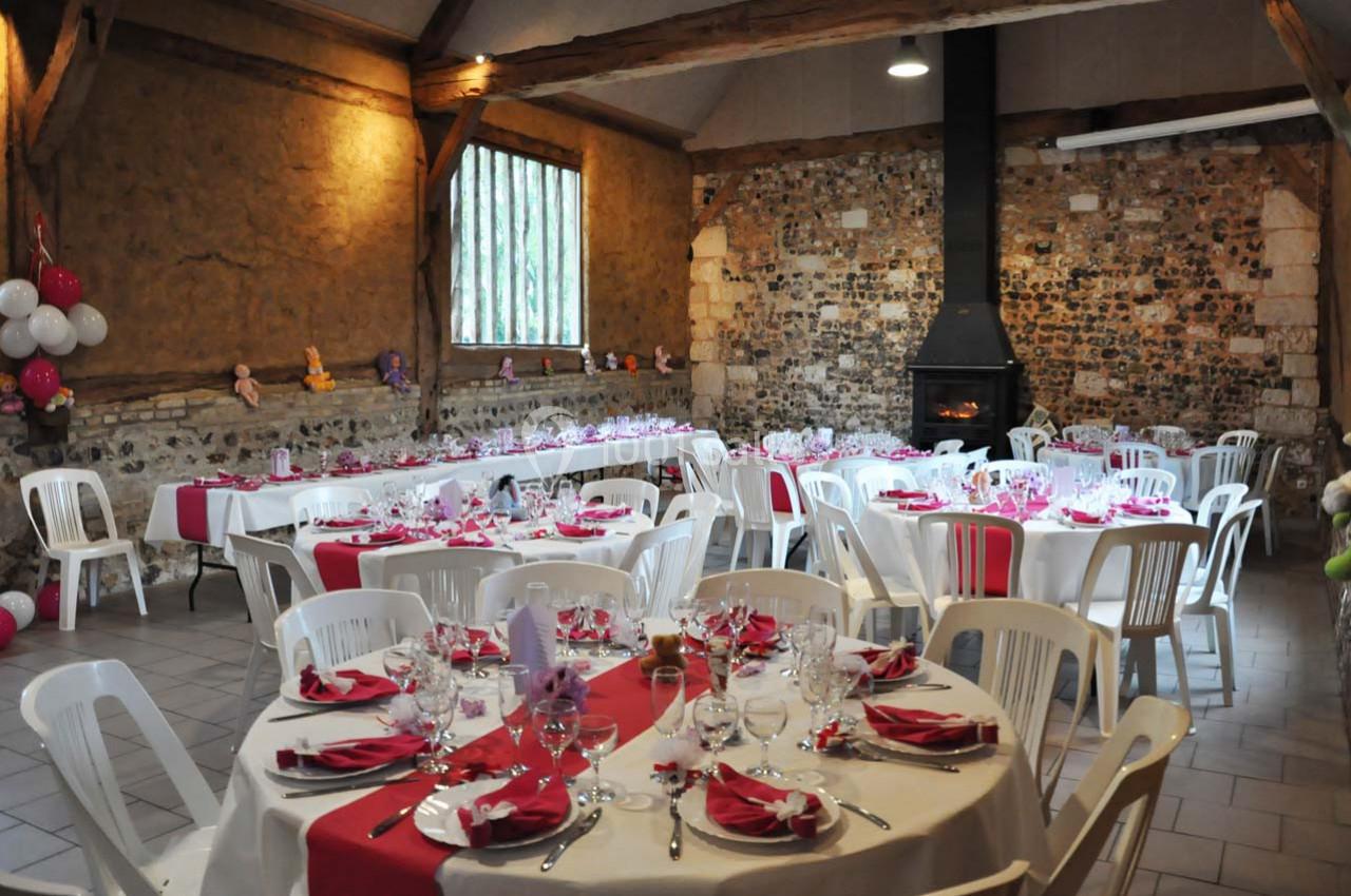 Location salle Montivilliers (Seine-Maritime) - Ferme d'Epaville #20 Salle de réception rustique décorée pour un événement, avec tables rondes dressées et nappes blanches et rouges.