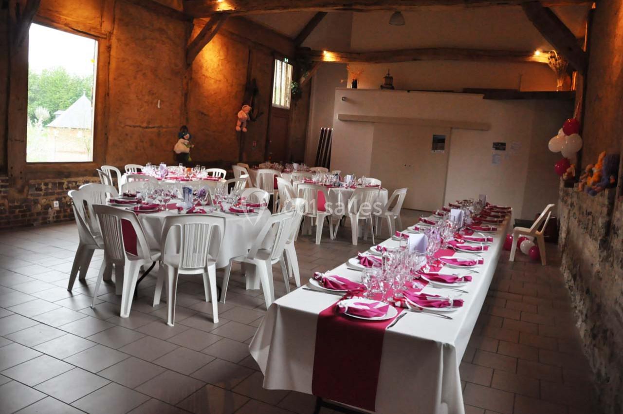 Location salle Montivilliers (Seine-Maritime) - Ferme d'Epaville #14 Salle décorée pour un repas festif avec des tables alignées, nappes blanches et accents rouges, chaises en plastique.