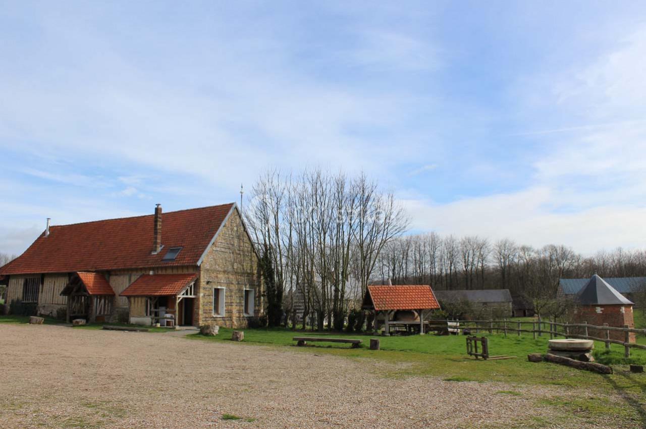 Location salle Montivilliers (Seine-Maritime) - Ferme d'Epaville #24 Bâtiments en pierre avec toits rouges dans un paysage rural, entourés d'arbres et d'une cour dégagée.