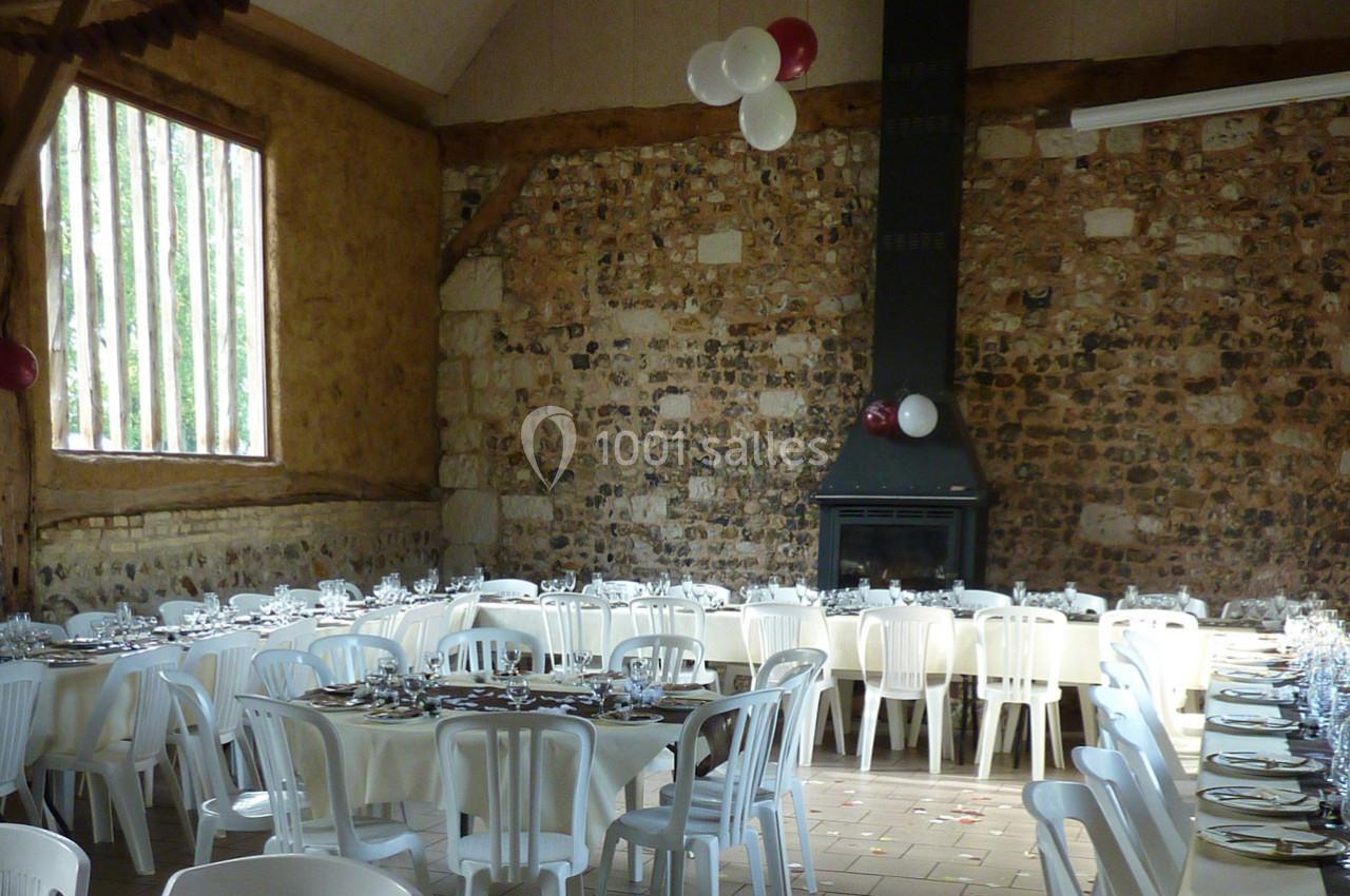 Location salle Montivilliers (Seine-Maritime) - Ferme d'Epaville #22 Salle rustique avec murs en pierre, tables dressées avec nappes blanches et chaises en plastique, décorée de ballons.