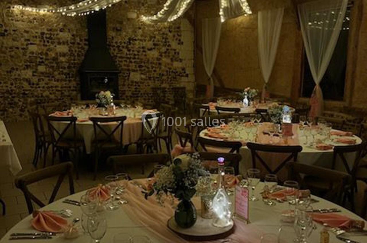 Location salle Montivilliers (Seine-Maritime) - Ferme d'Epaville #7 Salle de réception décorée avec des tables rondes, nappes blanches, serviettes roses et éclairage tamisé.