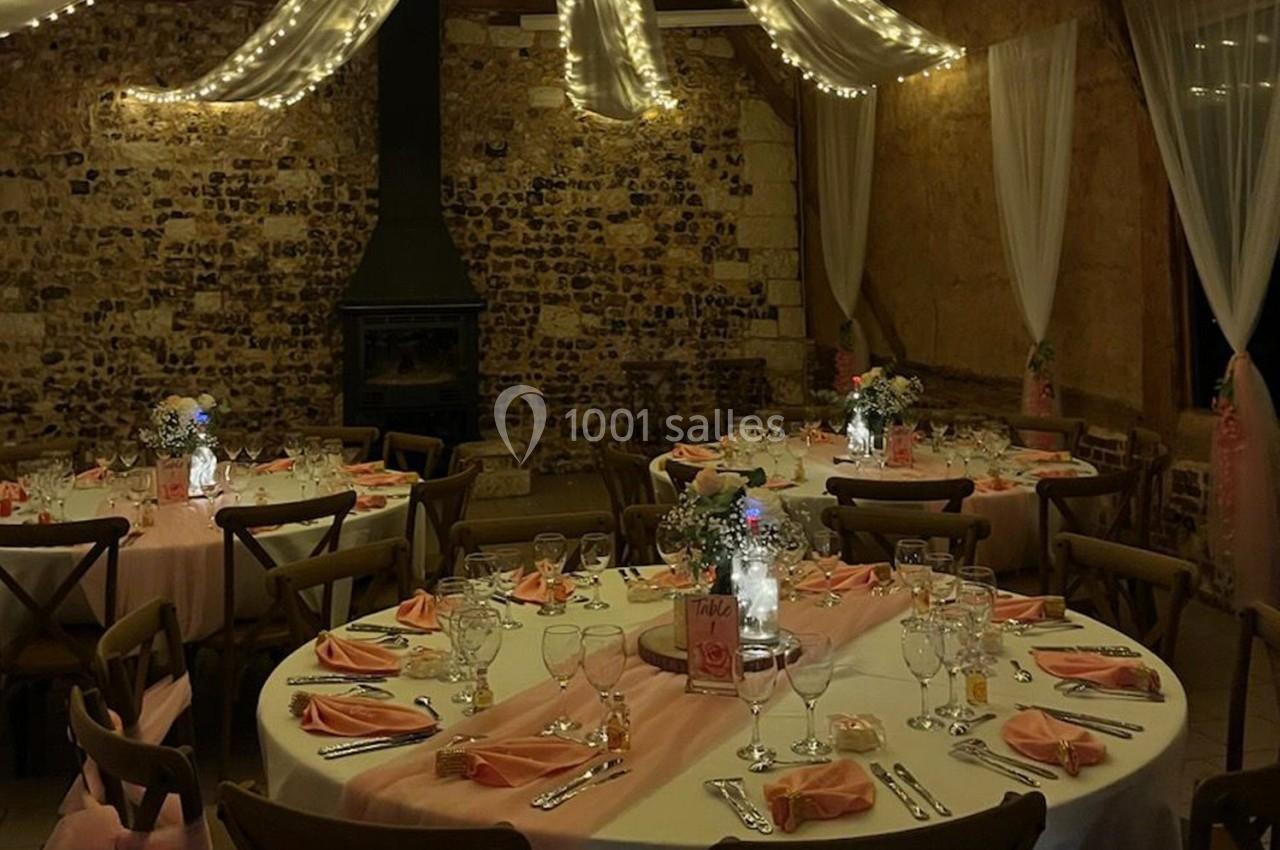 Location salle Montivilliers (Seine-Maritime) - Ferme d'Epaville #38 Salle de réception décorée avec des tables rondes, nappes roses, centres de table fleuris et guirlandes lumineuses…