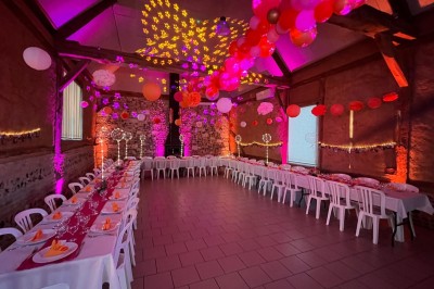 Miniature Location salle Montivilliers (Seine-Maritime) - Ferme d'Epaville #3 Grande table décorée pour un dîner, avec bougies et guirlandes lumineuses, dans une salle en pierres apparentes.