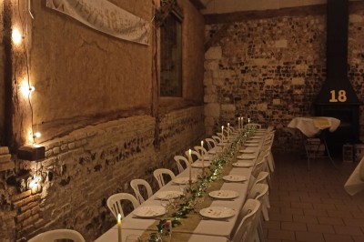 Miniature Location salle Montivilliers (Seine-Maritime) - Ferme d'Epaville #42 Grande table décorée pour un dîner, avec bougies et guirlandes lumineuses, dans une salle en pierres apparentes.