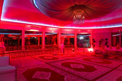 Cérémonie de mariage en plein air avec des invités assis, un couple avançant vers une arche décorée.