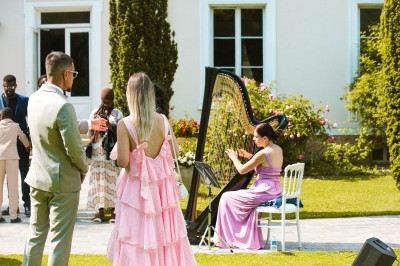 Cérémonie de mariage en plein air avec des invités assis, un couple avançant vers une arche décorée.