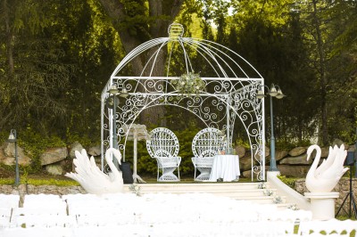 Cérémonie de mariage en plein air avec des invités assis, un couple avançant vers une arche décorée.
