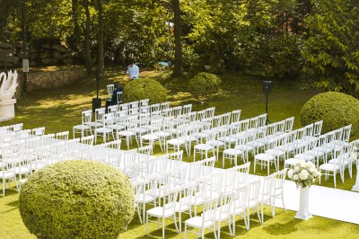 Cérémonie de mariage en plein air avec des invités assis, un couple avançant vers une arche décorée.