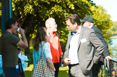 Salle lumineuse avec des stands promotionnels, des affiches et des tables recouvertes de nappes bleues, entourées de chaises…