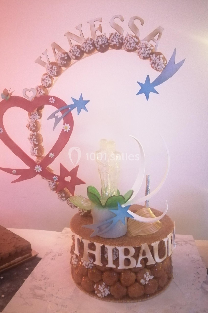 Pièce montée en choux décorée de motifs en sucre, avec les prénoms ’Vanessa’ et ’Thibaut’ en haut et en bas.