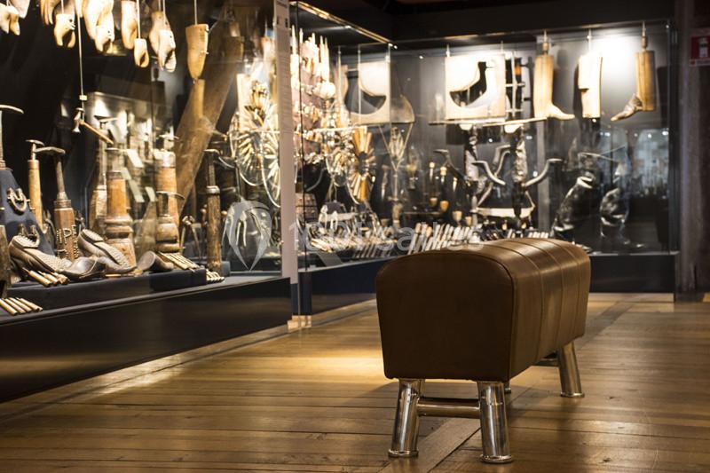 Banc en cuir devant une vitrine exposant divers objets anciens en métal et en bois dans un musée.