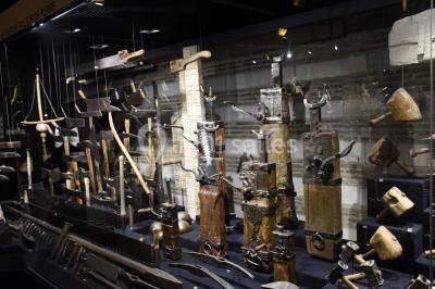 Rangée de limes métalliques suspendues avec des manches en bois dans un atelier ou une exposition artisanale.