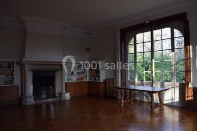 Cuisine lumineuse avec table en bois et nappe à carreaux rouges, chaises, plan de travail en métal et fenêtre ouverte.