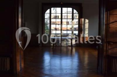 Cuisine lumineuse avec table en bois et nappe à carreaux rouges, chaises, plan de travail en métal et fenêtre ouverte.