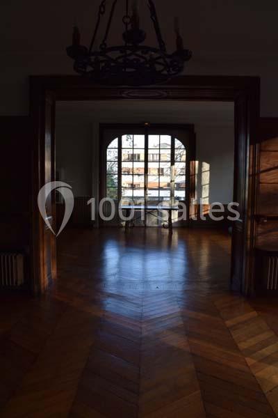 Vue d'une pièce vide avec parquet en bois, grande fenêtre donnant sur un immeuble et lumière naturelle.