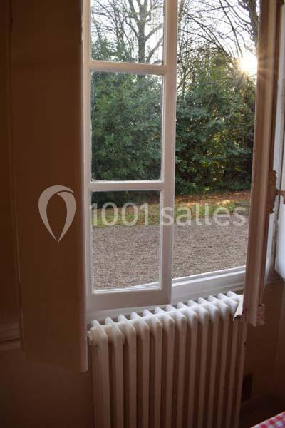 Fenêtre ouverte donnant sur un jardin avec des arbres, vue depuis l'intérieur près d'un radiateur.