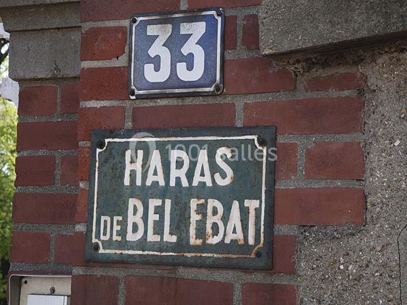 Plaques sur un mur en briques indiquant ’33’ et ’Haras de Bel Ebat’.