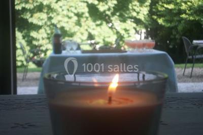 Cuisine lumineuse avec table en bois et nappe à carreaux rouges, chaises, plan de travail en métal et fenêtre ouverte.