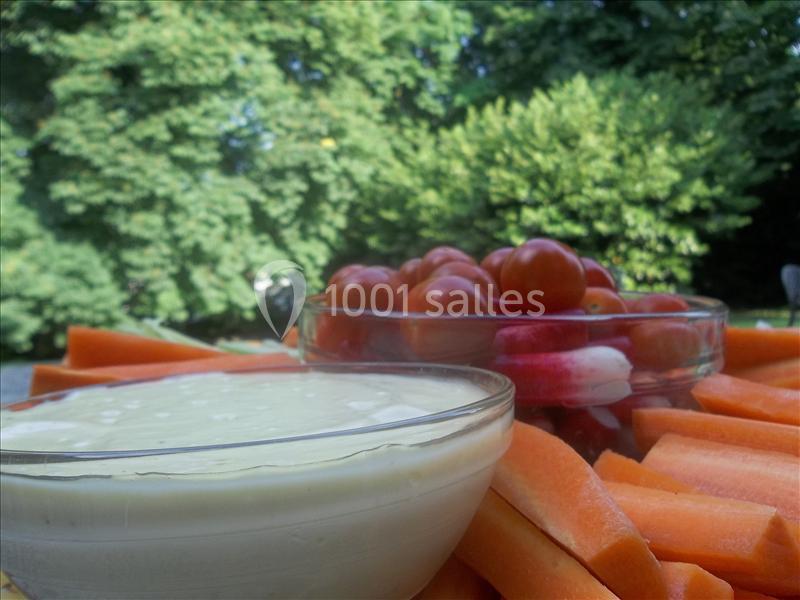 Bol de sauce blanche au premier plan avec des bâtonnets de carottes, radis et tomates cerises en arrière-plan.