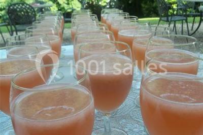 Cuisine lumineuse avec table en bois et nappe à carreaux rouges, chaises, plan de travail en métal et fenêtre ouverte.